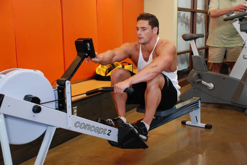 Rowing machine stroke showing a tall catch, legs initiating the drive, slight torso swing, handle finishing below the ribs, and controlled recovery